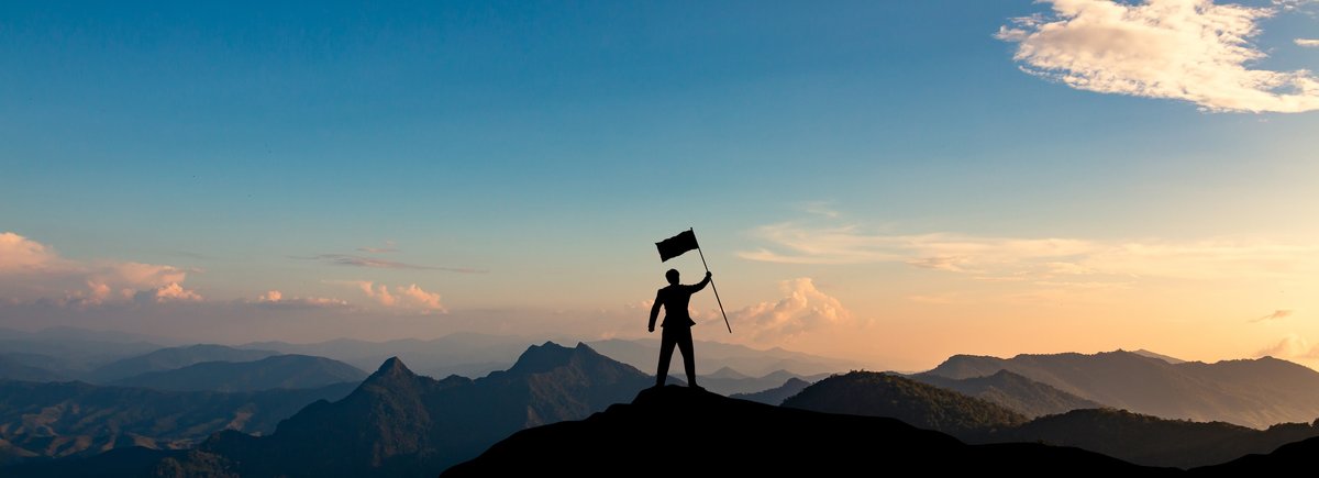 person waving flag having reached mountain summit